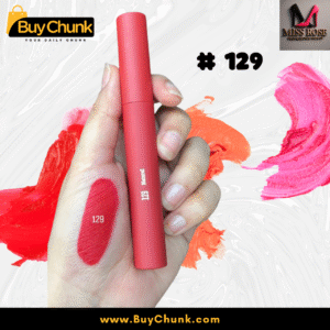 A close-up of a hand swatched with Miss Rose Matte Lip Gloss Shade 129, showing the rich rosy-red color, with the lip gloss tube being held.